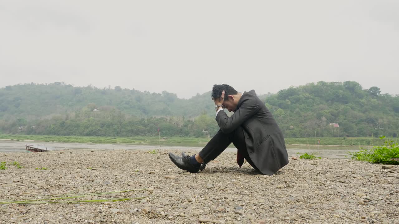 Businessman sitting alone by the river, stressed