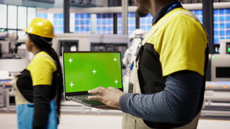 vertical video factory engineer using green screen laptop to calibrate high tech machinery