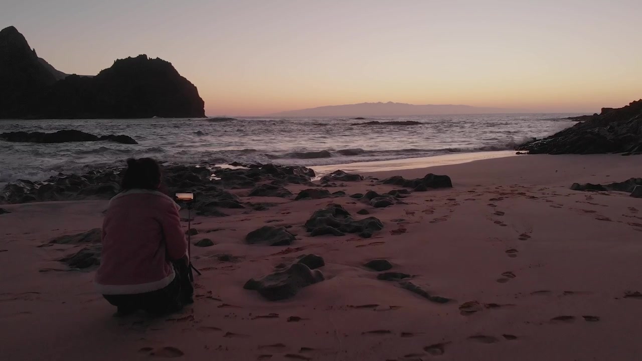 Aerial shot over Woman on beach shore taking sunset photos, Porto Santo Island