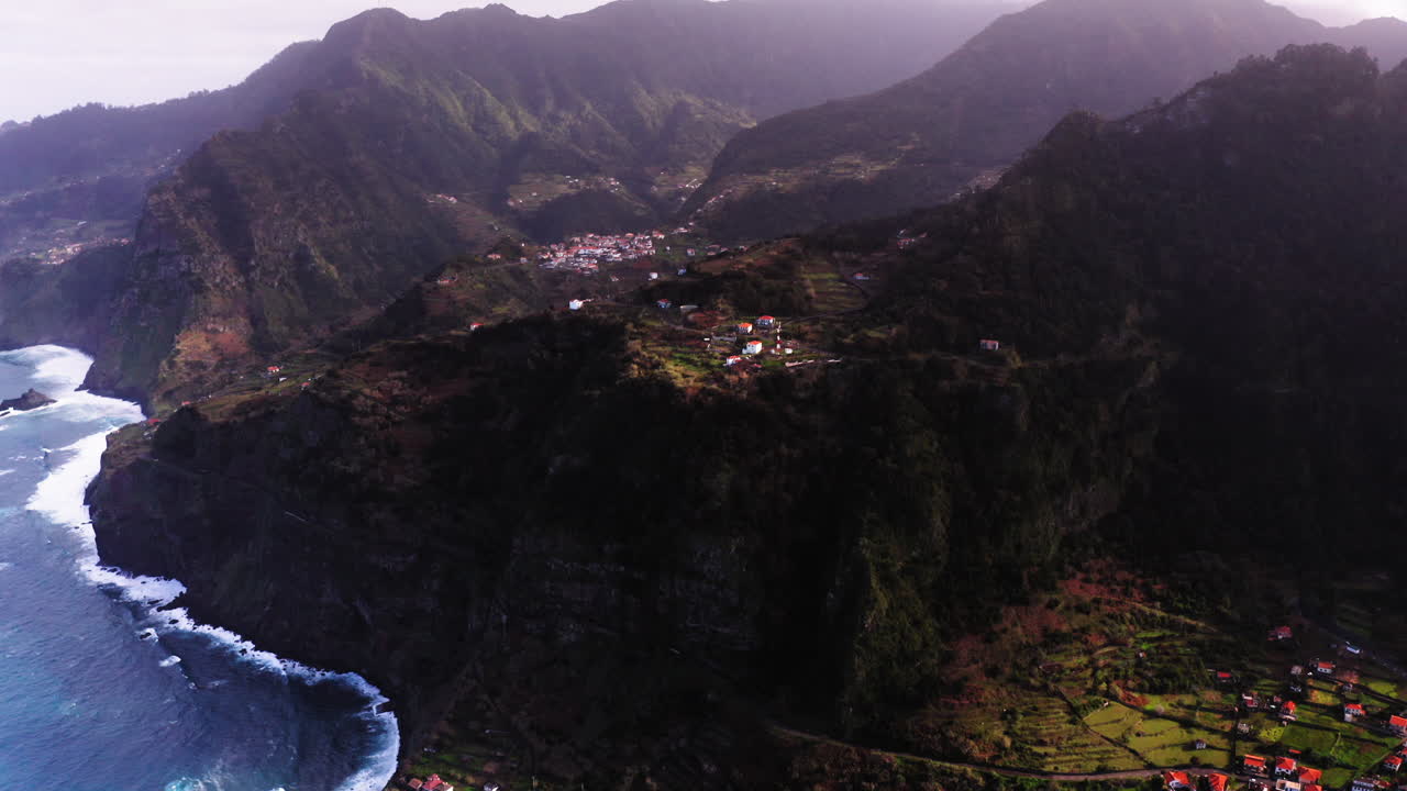Toma aérea a vista de pájaro de la ciudad de Ponta Delgada, rodeada de montañas rocosas y el océano al pie del acantilado.