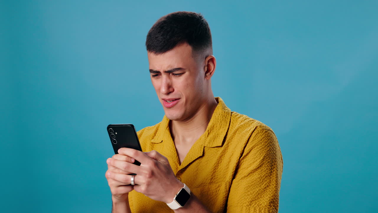 Man looking at smartphone with upset expression