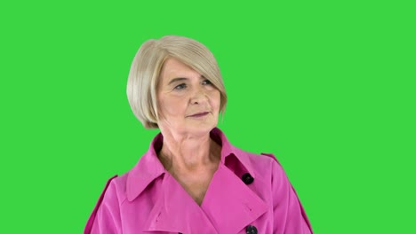 smart lady in pink trench coat standing, waiting and thinking on a green screen, chroma key