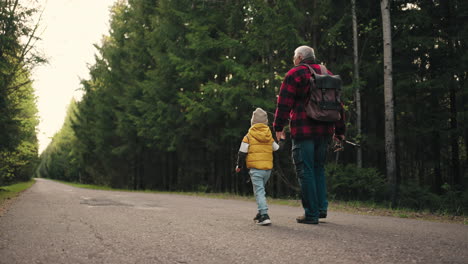 Der-Alte-Fischer-Und-Sein-Kleiner-Enkel-Gehen-Morgens-Auf-Der-Straße-Durch-Den-Wald.-Opa-Trägt-Eine-Angel