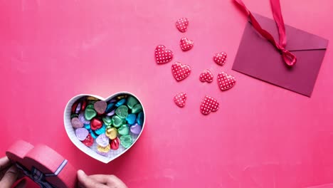 heart-shaped gift box with candies and a maroon envelope