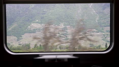 vista por la ventana de un tren que atraviesa el paisaje montañoso de suiza
