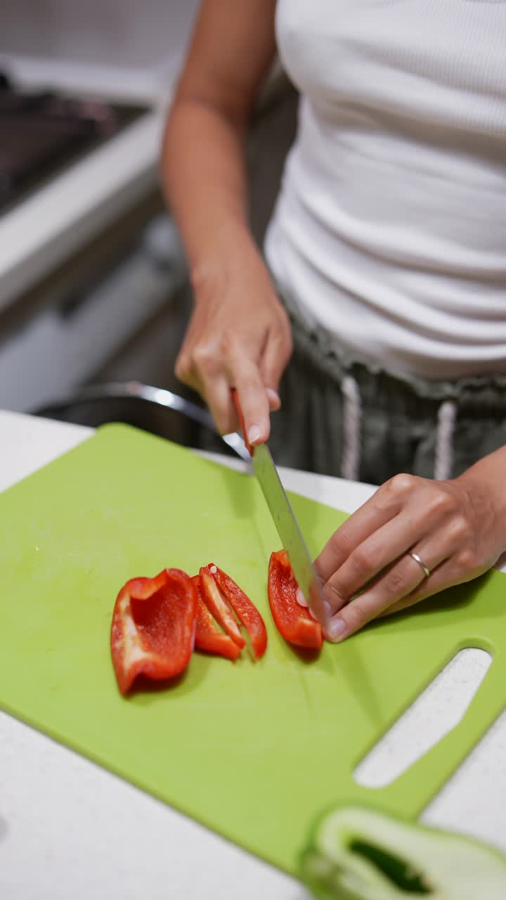 mujer cortando pimientos de campana roja en la cocina