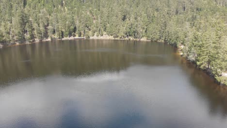 Toma-Aérea-De-Pedestal-Del-Lago-Mummelsee-Con-Nubes-Y-Reflejos-Del-Cielo-En-El-Agua