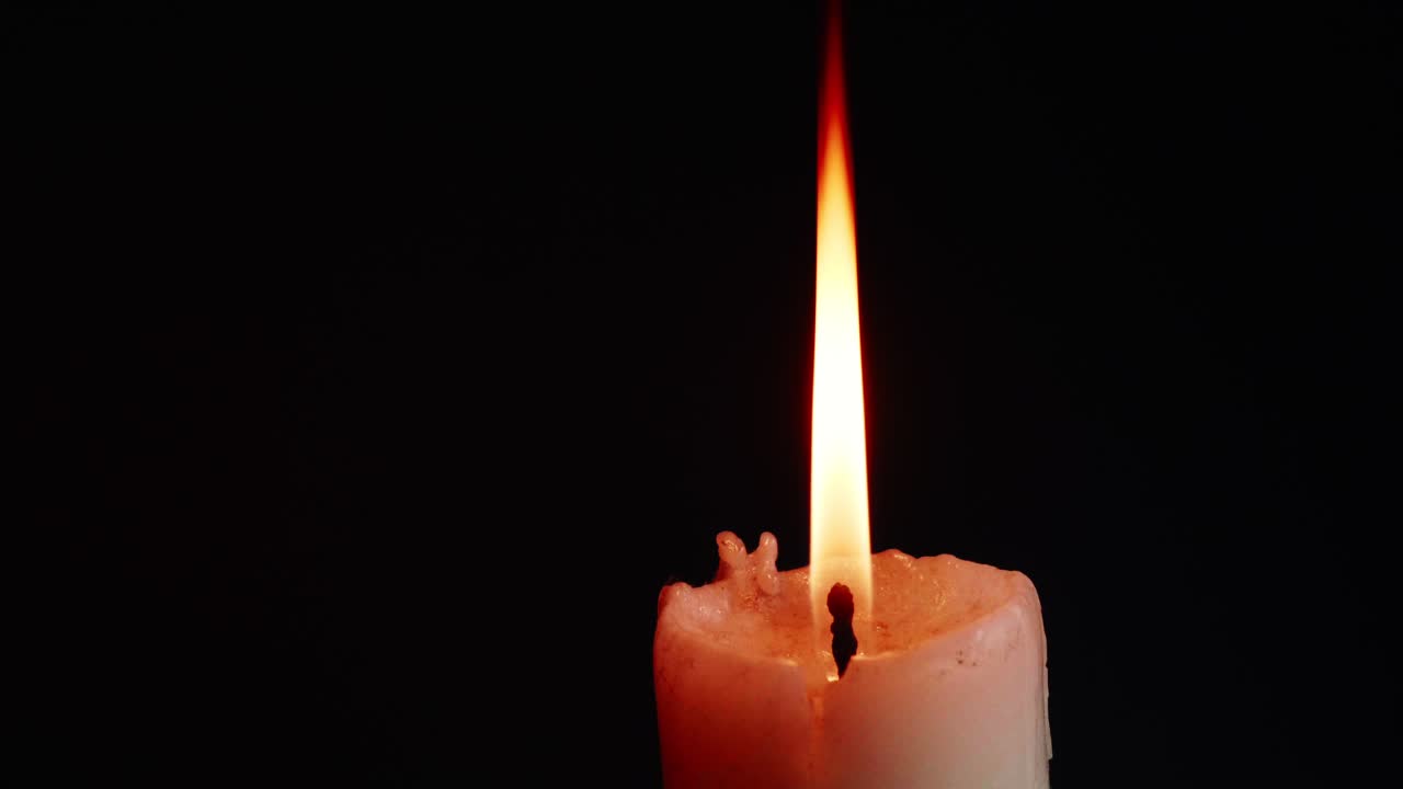 las vitrinas de coloridas velas individuales sobre fondo negro con el efecto de la luz y la cámara lenta