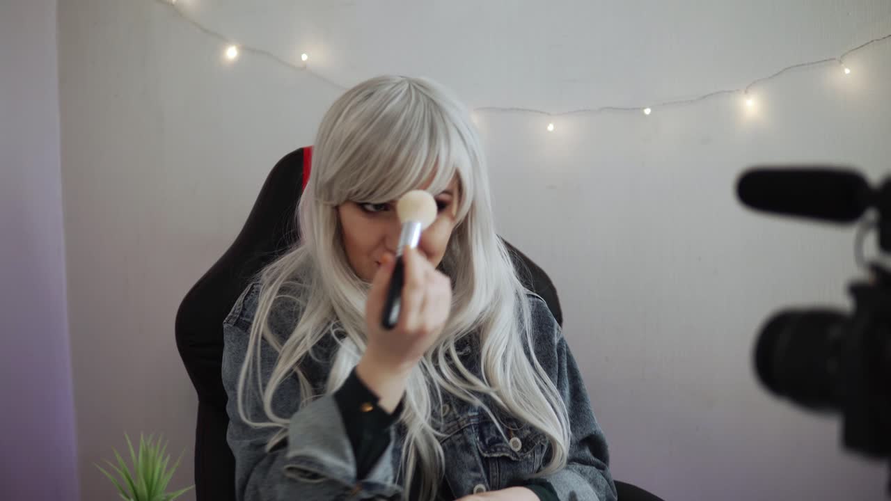 여성 동영상 블로거가 전문 카메라 앞에서 파우더 화장품을 테스트하고 검토하고 있습니다.