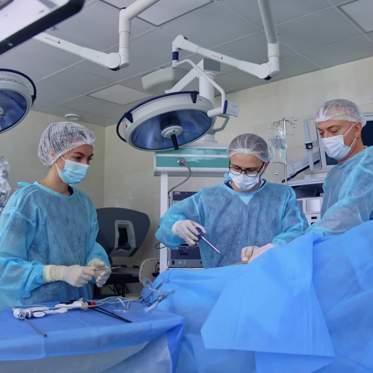 Medical team performing operation. Group of surgeons at work in operating theater toned in blue