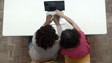 Top-view-of-women-working-with-laptop-while-sitting-at-table