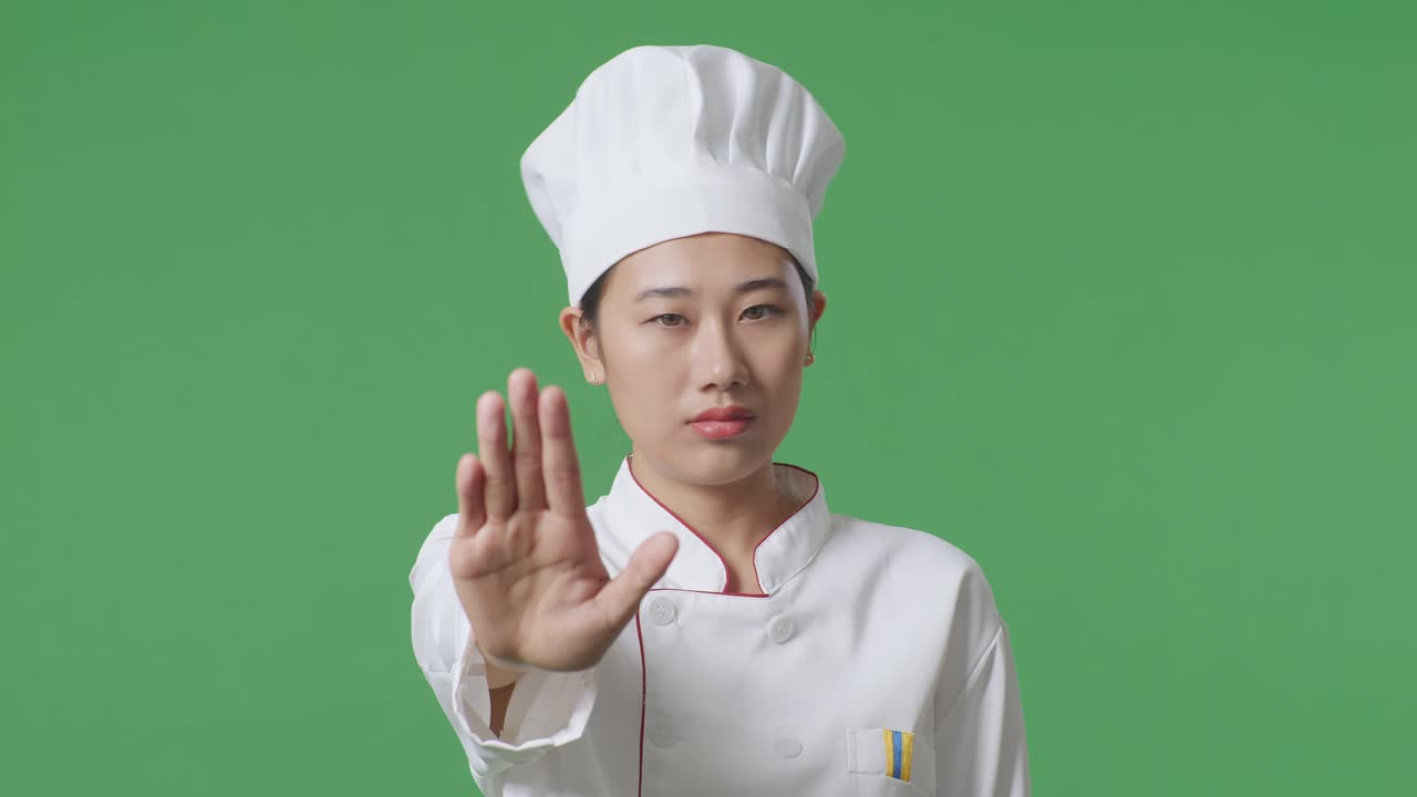 Close Up Of Asian Woman Chef Looking At Camera And Disapproving With No Hand Sign In The Green Screen Background Studio