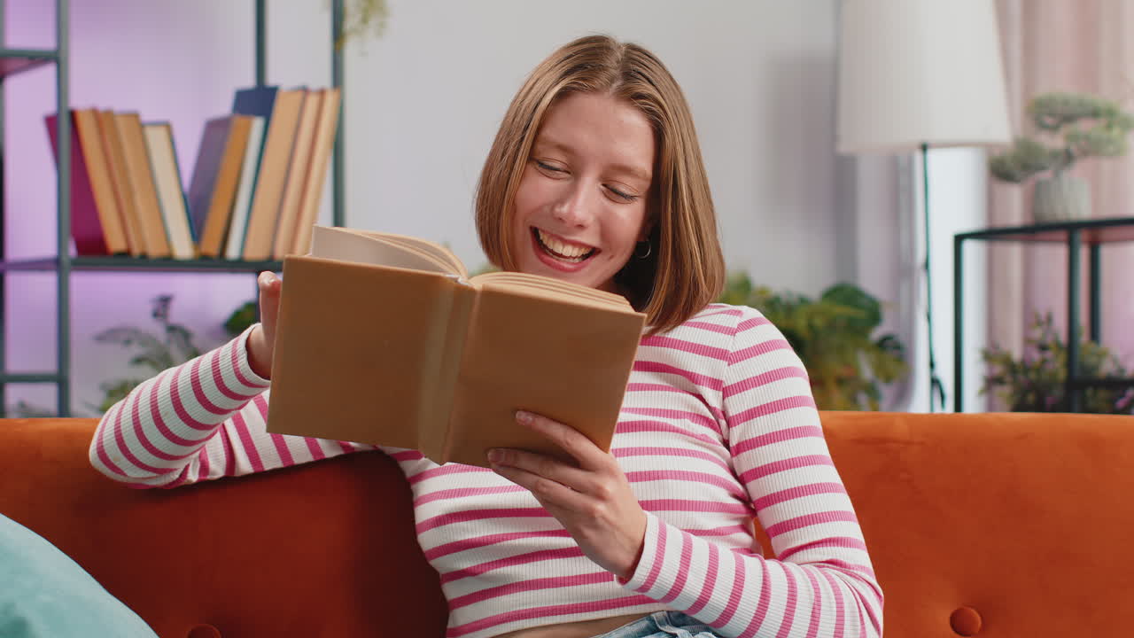 mujer joven relajándose libro interesante volteando páginas sonriendo disfrutando de la literatura descansando en el sofá