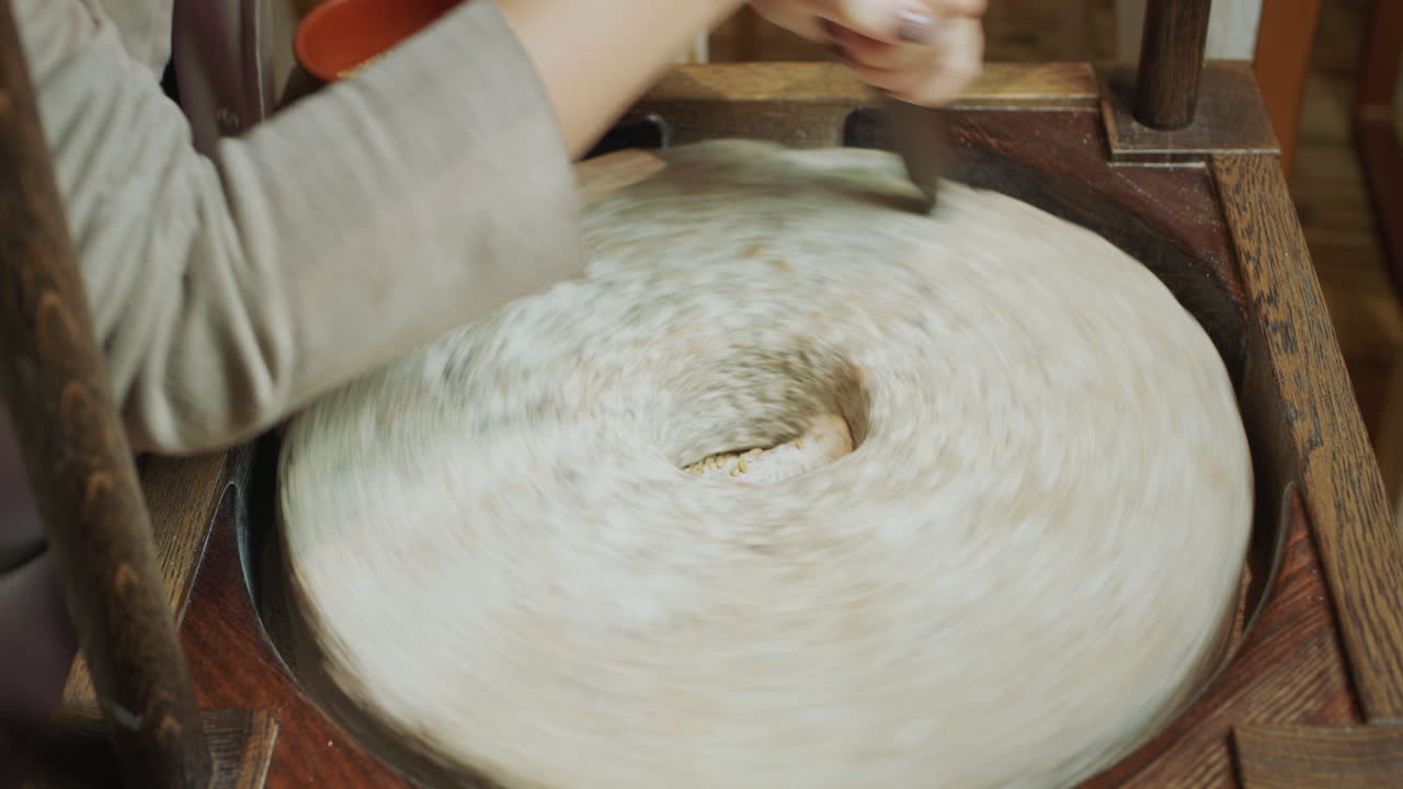 el panadero muele el grano en harina. molino de mano antiguo en funcionamiento con una auténtica piedra de molino de 200 años