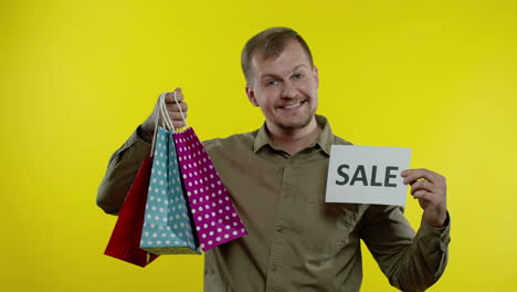 happy man showing sale word inscription, smiling, looking satisfied with low prices. slow motion