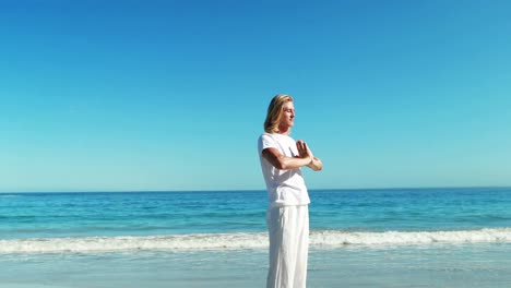 man performing yoga at beach