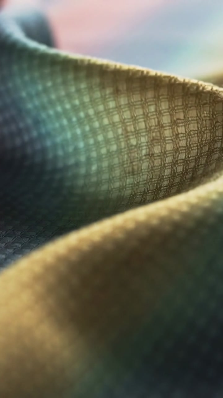 Camera shifting across folded textile, revealing tight grid and open lattice for textile design