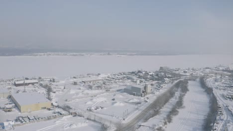 aerial view of a snowy city by a frozen lake