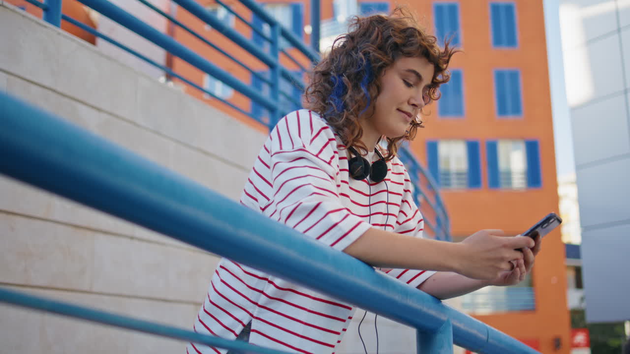 adolescente despreocupado navegando aplicación teléfono inteligente en el distrito de la ciudad. mujer mensajería en línea