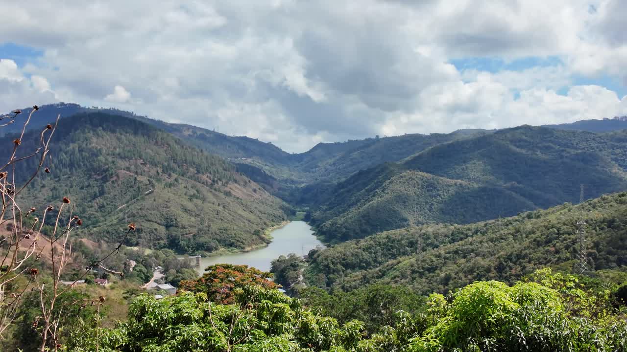 Pemandangan geser kanan di atas waduk La Mariposa dan pegunungan hijau subur