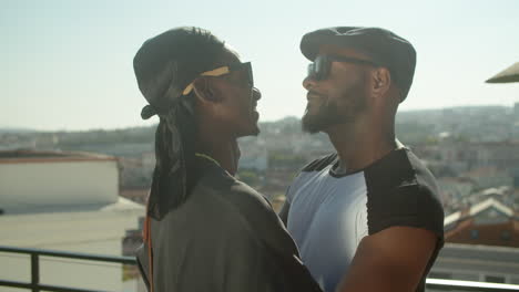 side view of afro-american gays standing on rooftop and hugging