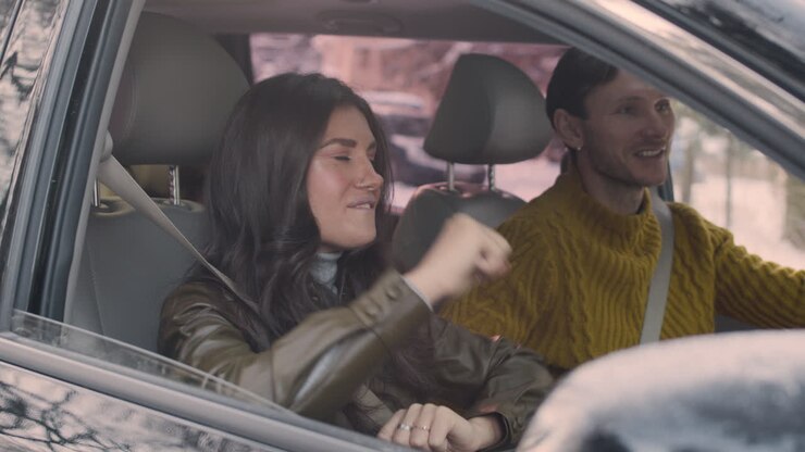 Marito e moglie seduti sui sedili anteriori di un'auto.