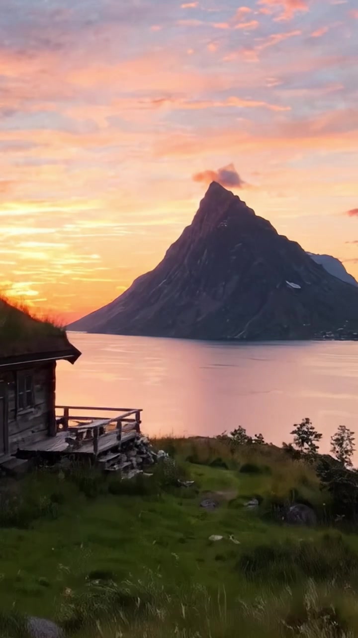 Betagende solnedgang over majestætisk bjerg, der spejler sig i roligt vand med frodigt grønt i forgrunden, der viser naturens fantastiske skønhed og ro