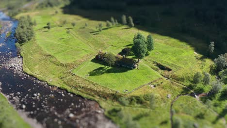 an aerial view of a traditional sod roof cabin on the river bank