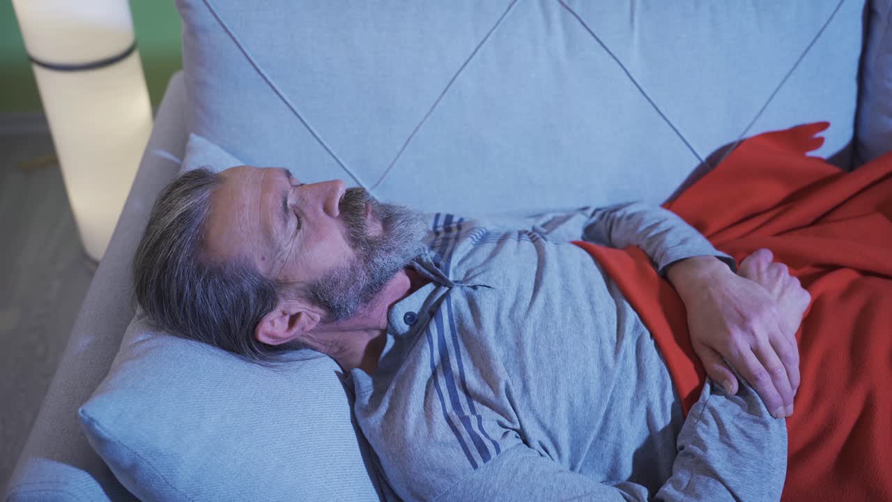 el hombre que duerme por la noche tiene pesadillas y se despierta asustado.