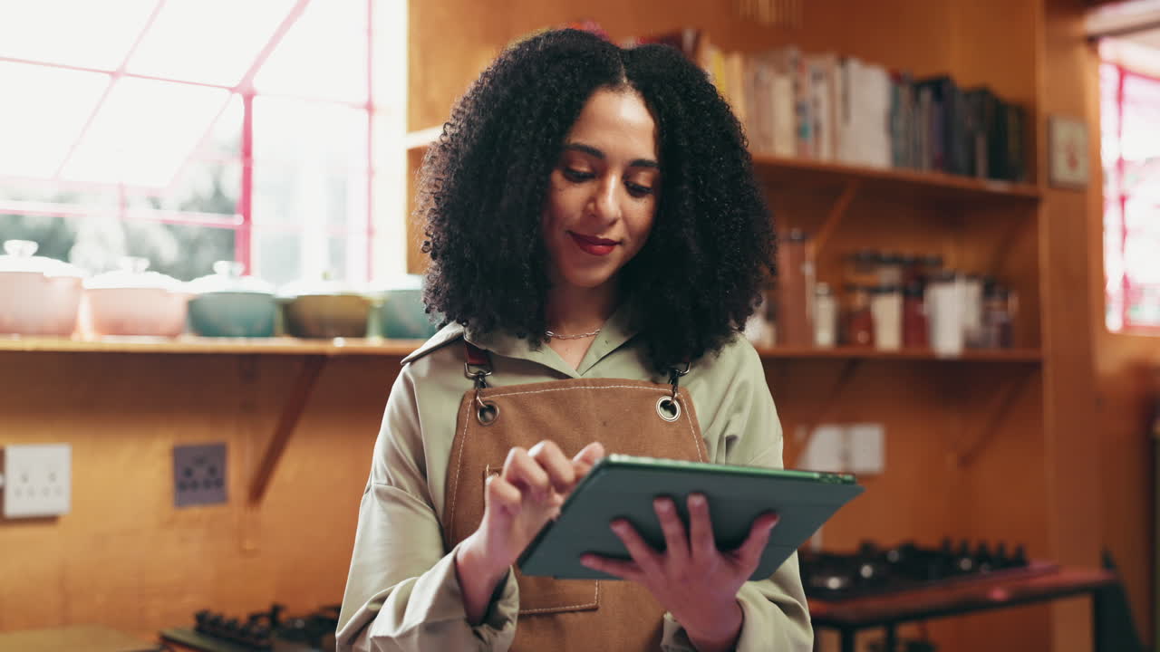Woman in apron using tablet in cafe