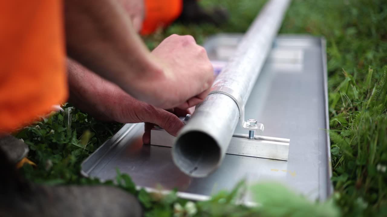 Closeup view of road workers fastening bolts on sign post on grassy field