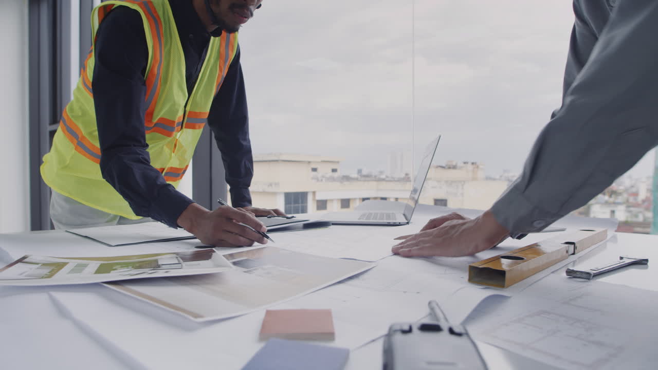 Engineers Drawing Blueprints of Room in Construction Site