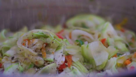 sprinkling oregano on a vegan sauté of vegetables