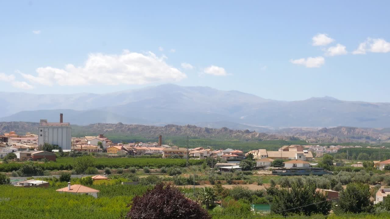 Panoramic view of Benalúa, a village in the province of Granada, Spain. Houses, green fields, and a large silo can be seen