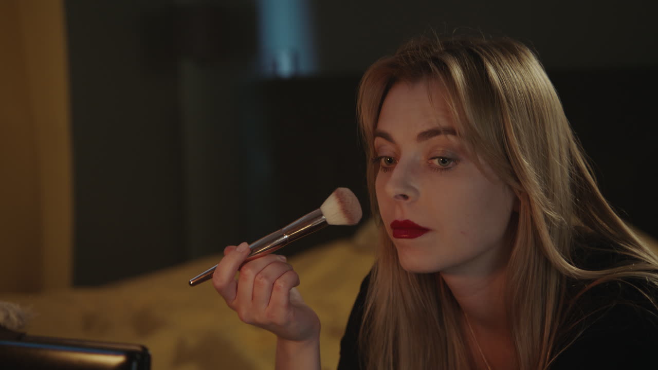 Woman Applying Makeup in Bedroom