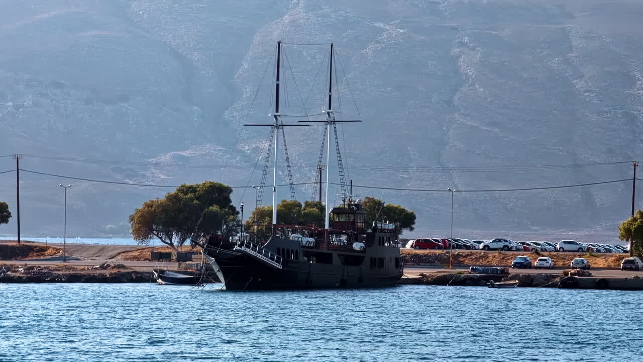 Slow motion landscape of wooden sailboat ship vessel with mast docked at wharf pier in Kissamos Port harbour Crete Greece Europe travel tourism nautical maritime fishing transport
