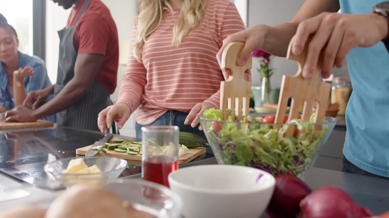 Glade venner med ulik bakgrunn lager mat på kjøkkenet, sakte film