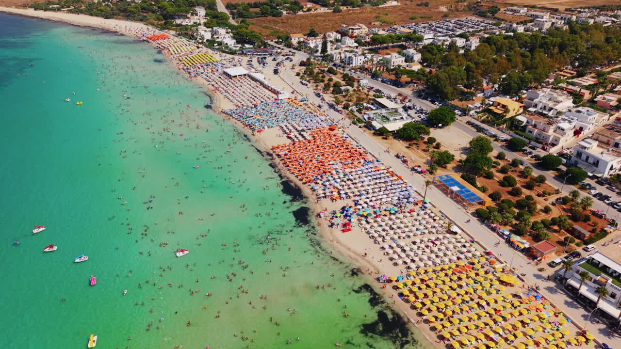 Vista aérea de uma praia lotada com guarda-chuvas coloridos