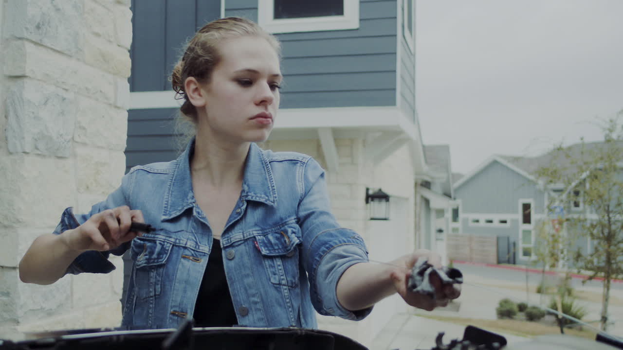 20대 초반의 여성이 트럭 후드 아래를 확인하고 기계적인 문제를 찾아 수리하기 위해 트럭 아래로 이동합니다.