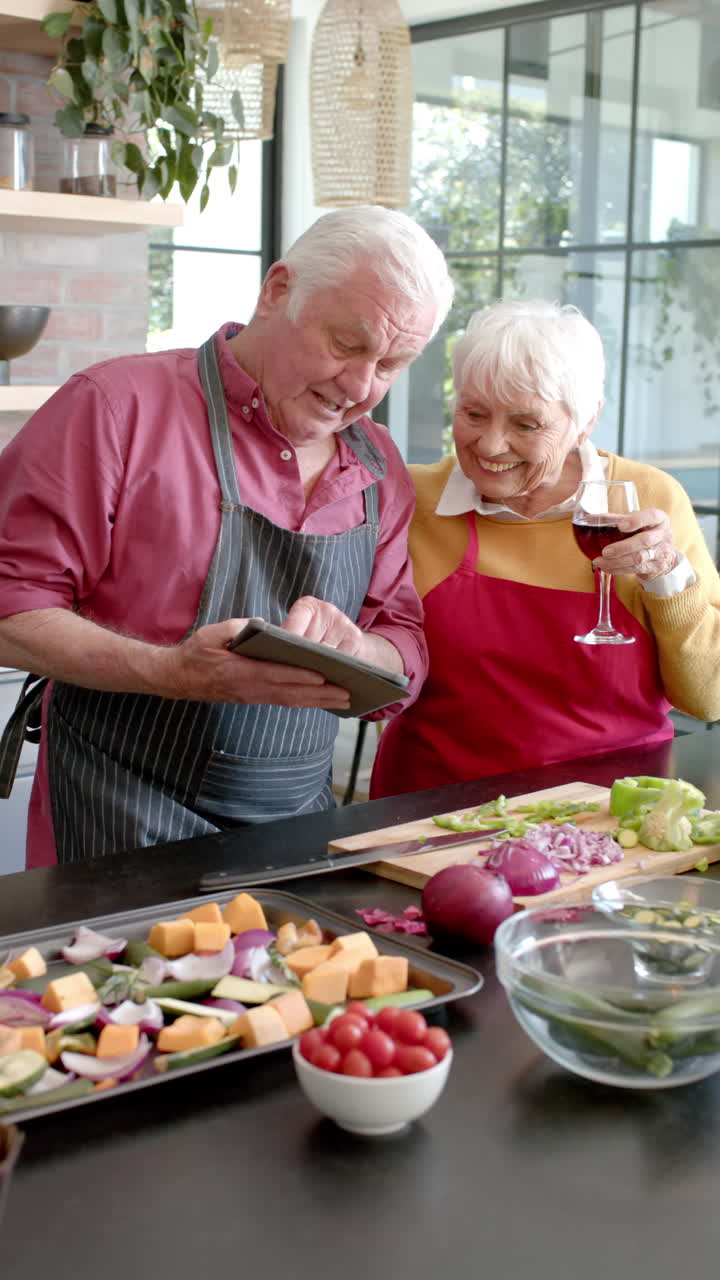 Vertical video of senior caucasian couple cooking dinner in kitchen, slow motion