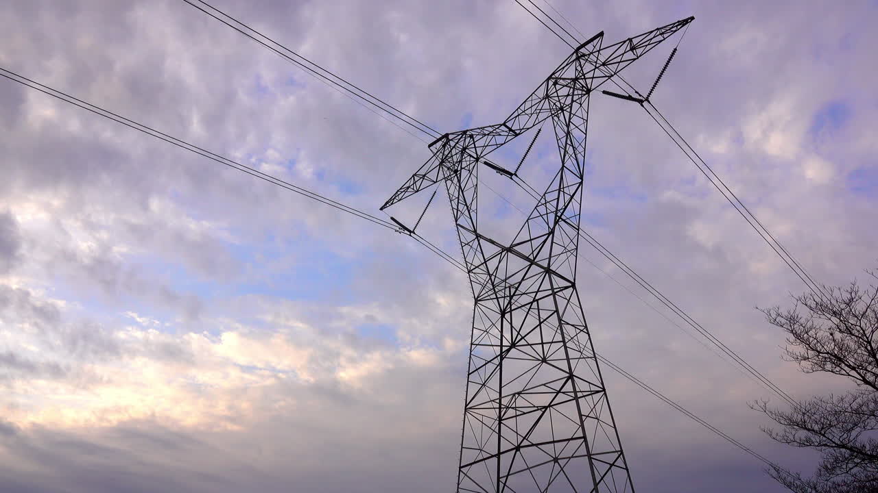 Large electrical pylon with partly cloudy sky behind
