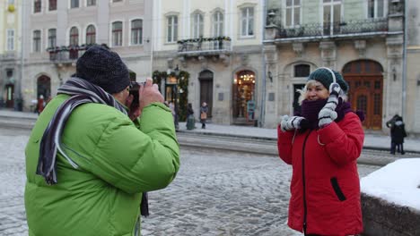 senior couple man woman tourists, grandfather taking photo pictures of grandmother on retro camera