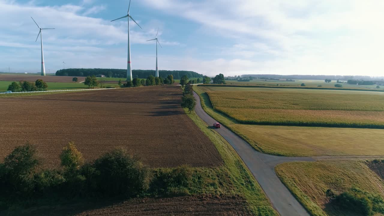 시골길 공중에서 풍력 터빈 근처를 운전하는 자동차
