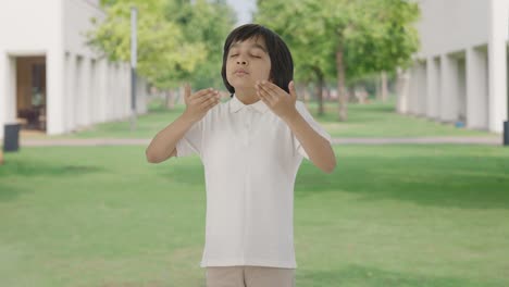 happy indian boy doing breathe in breathe out exercise in park