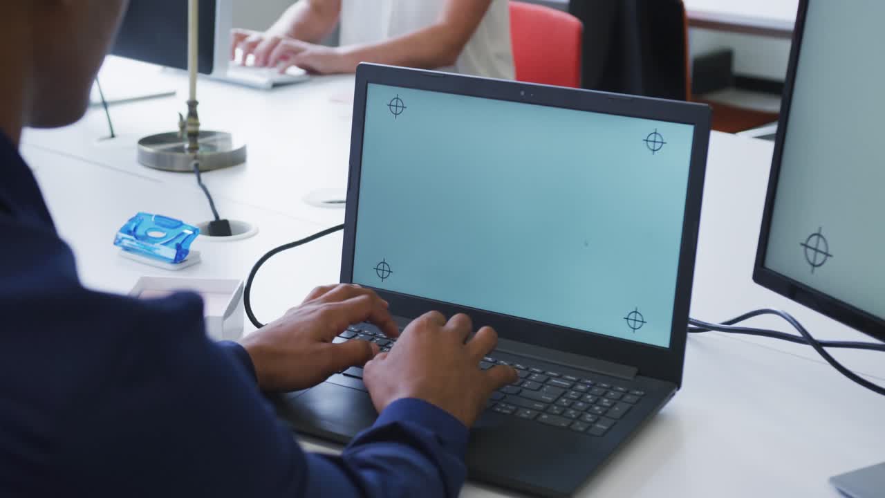 manos de un hombre de negocios de raza mixta usando una computadora portátil en el escritorio en la oficina