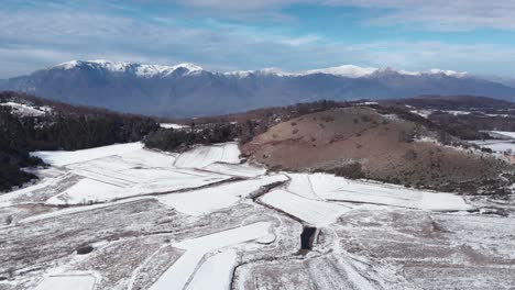 Slow-Aerial-ascending-over-snow-covered-mountain-forest-plains-sunny-Winter-Day