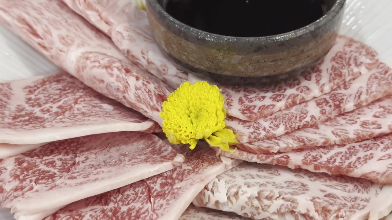 Primer plano de rebanadas de carne de res Wagyu A5 premium dispuestas en un plato de servir, destacando un marmoleado excepcional y una presentación elegante para una cena gourmet.
