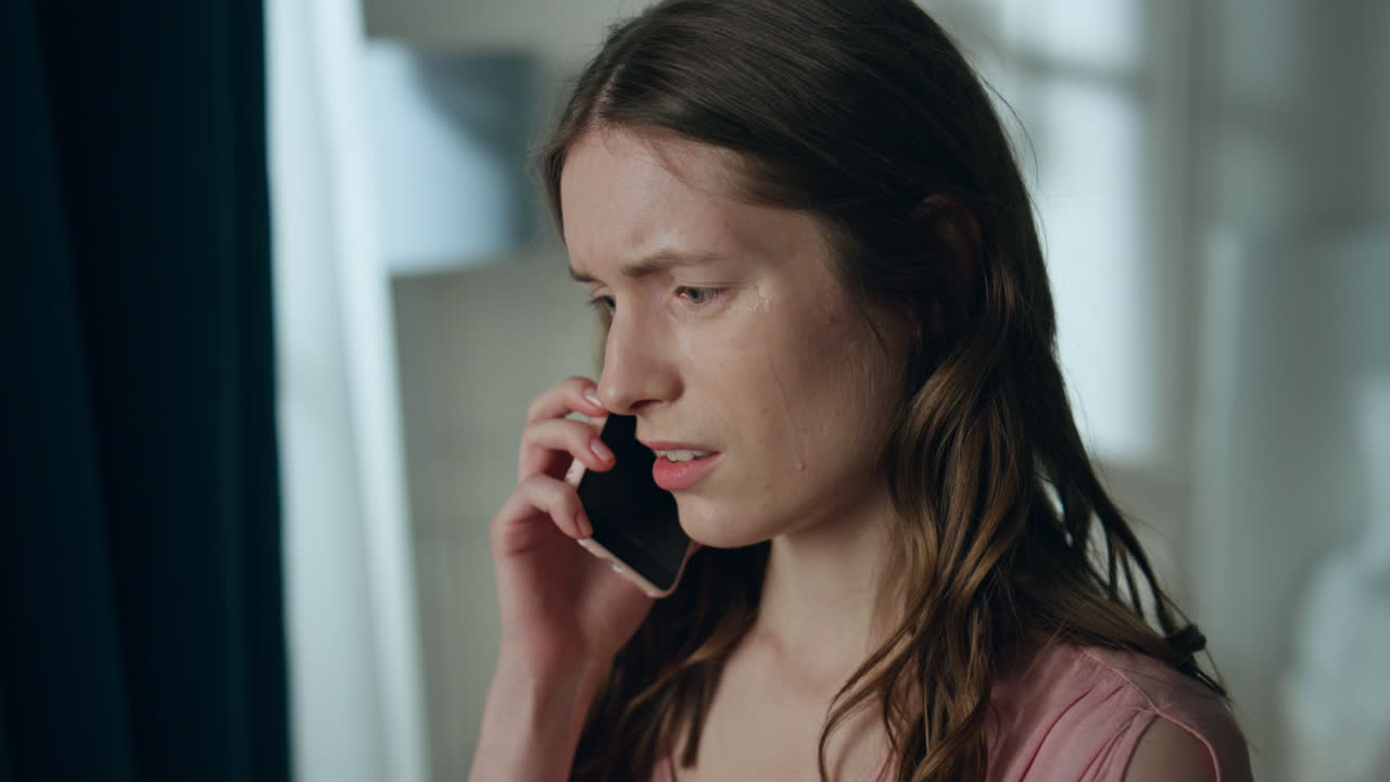 스트레스를 받은 소녀가 어두운 방에서 스마트폰으로 전화하고 있다.
