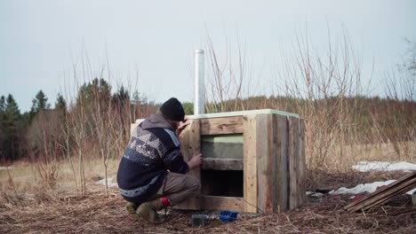 hombre construyendo su bañera de agua caliente al aire libre - toma amplia