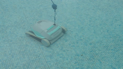 robotic pool cleaner moving across blue tile floor underwater in clear pool